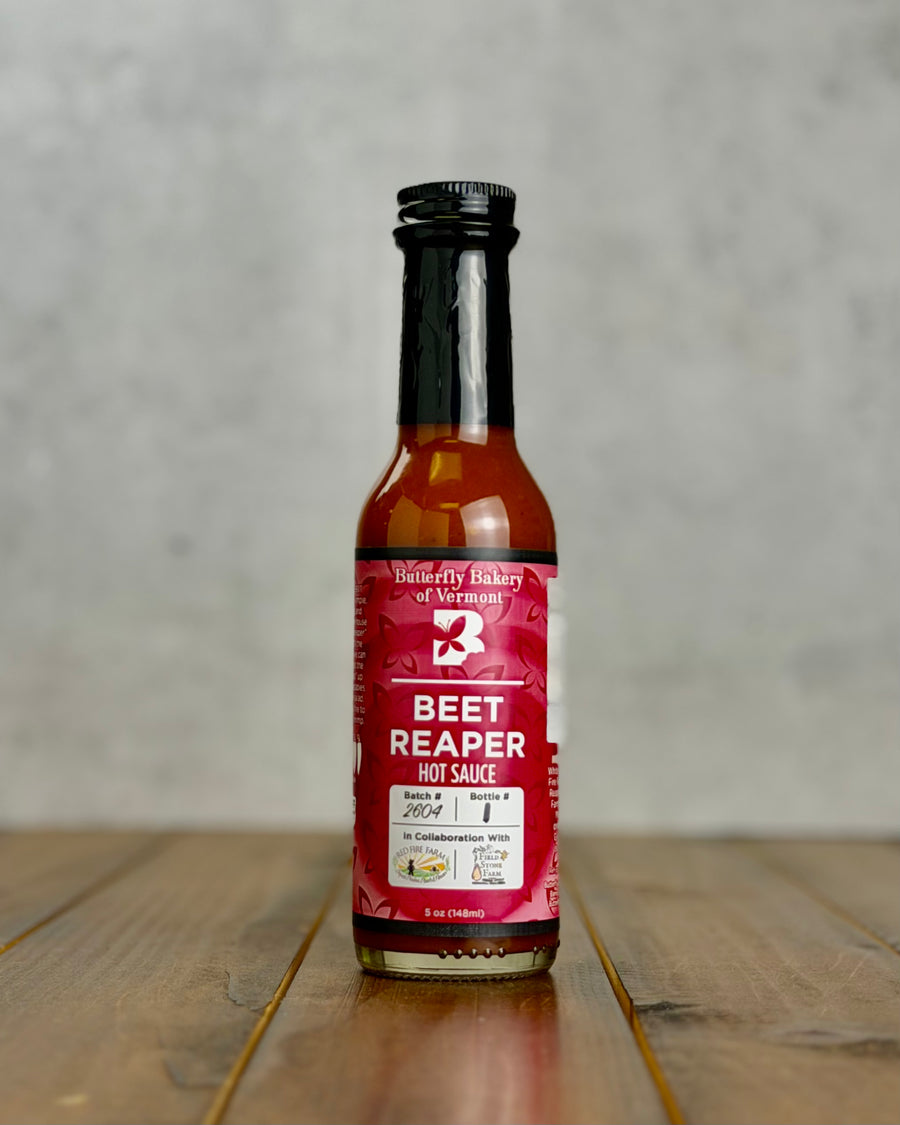 Bottle of Beet Reaper hot sauce from Butterfly Bakery of Vermont on a wooden tabletop