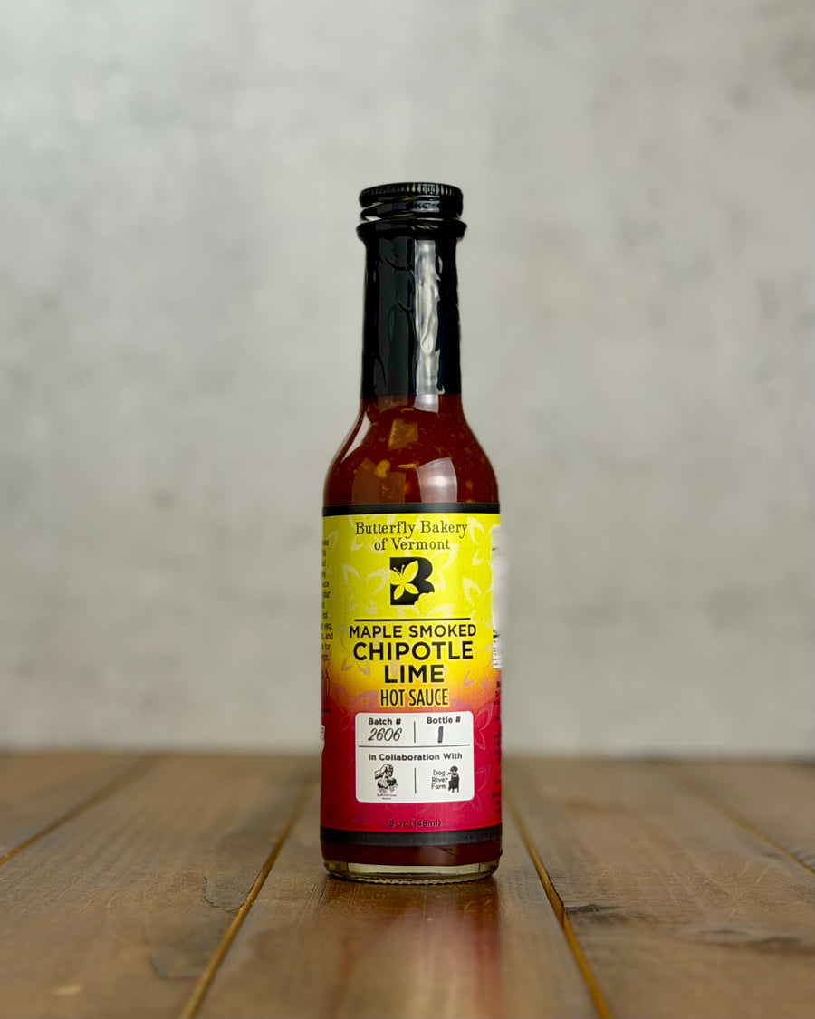 Bottle of Maple Smoked Chipotle Lime hot sauce from Butterfly Bakery of Vermont on a wooden tabletop