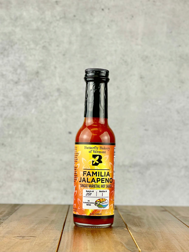 Bottle of Familia Jalapeno single varietal hot sauce from Butterfly Bakery of Vermont on a wood table