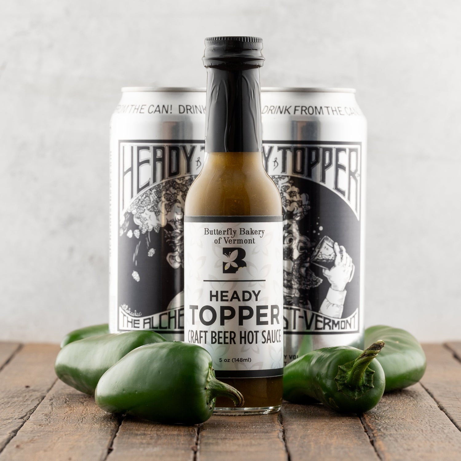 Heady Topper craft beer hot sauce with two cans on a wooden surface.