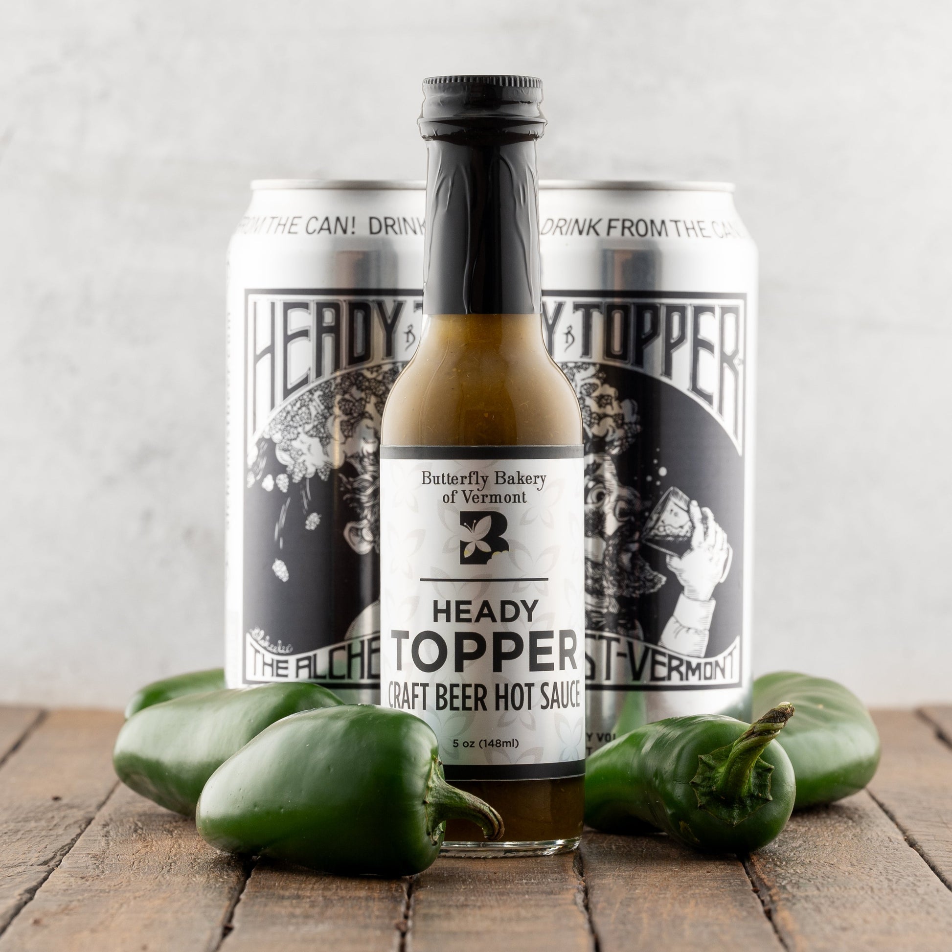 Heady Topper craft beer hot sauce with two cans on a wooden surface.