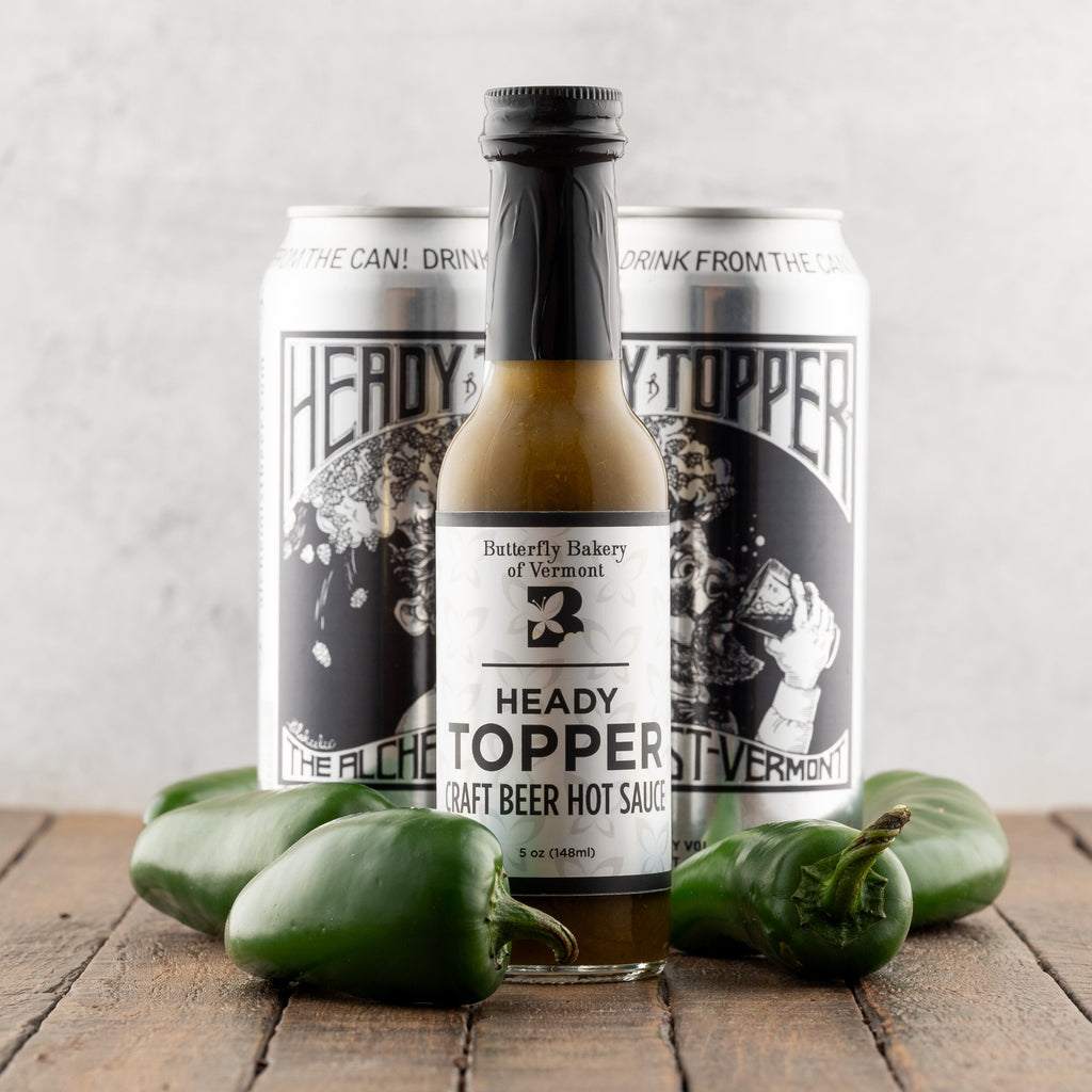 Heady Topper craft beer hot sauce with two cans on a wooden surface.