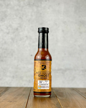 Bottle of Maple Chocolate Ghost hot sauce from Butterfly Bakery of Vermont on a wood table