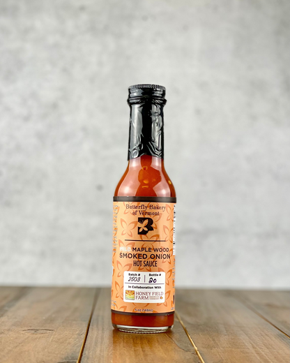 Bottle of Mild Maple Wood Smoked Onion hot sauce from Butterfly Bakery of Vermont on a wood table