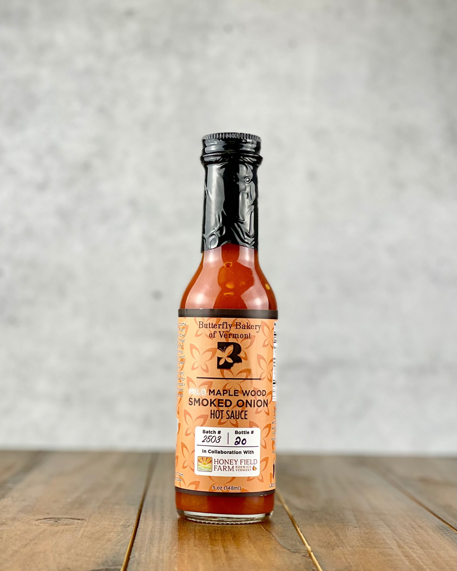 Bottle of Mild Maple Wood Smoked Onion hot sauce from Butterfly Bakery of Vermont on a wood table