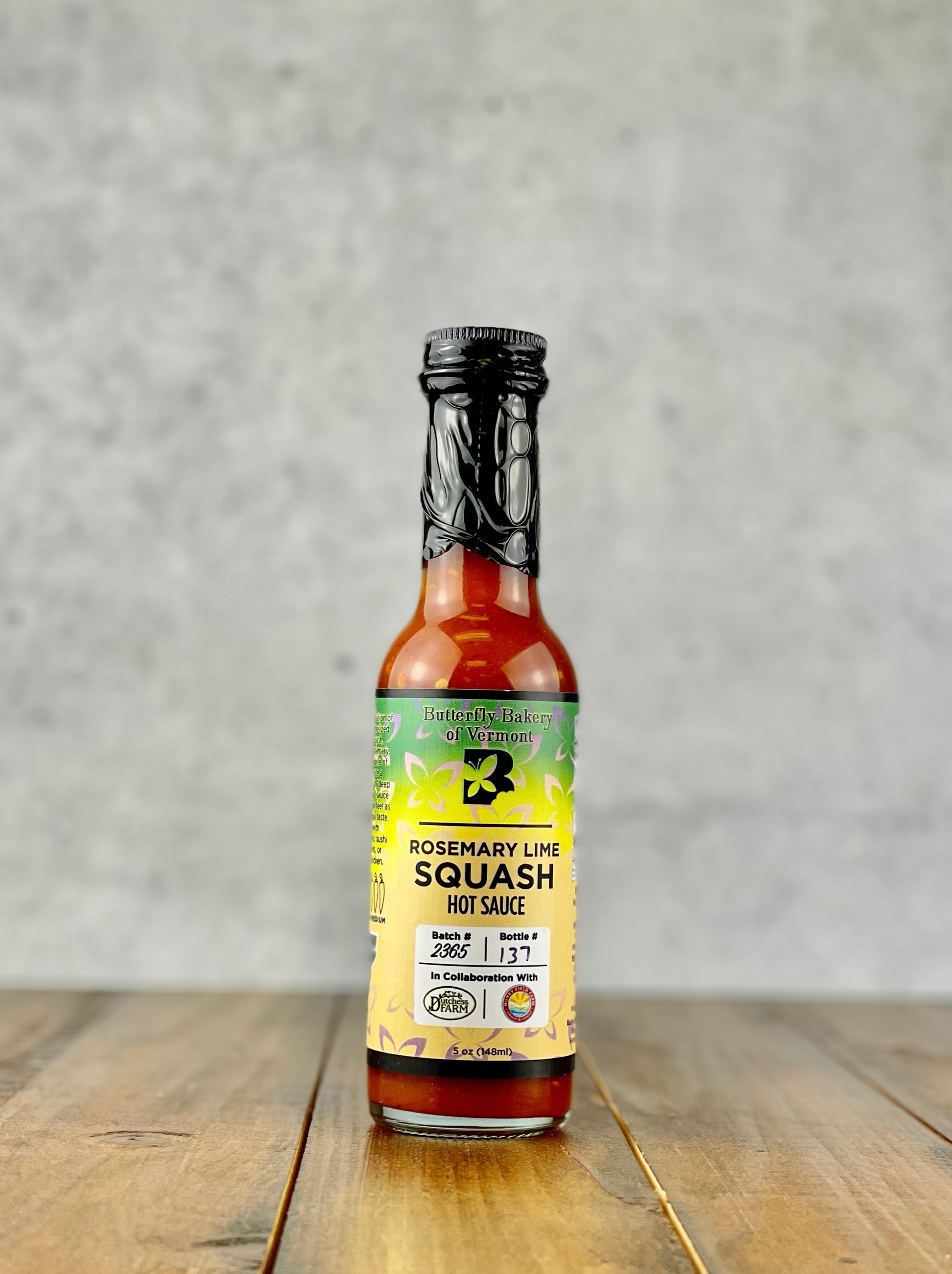 Bottle of Rosemary Lime Squash hot sauce from Butterfly Bakery of Vermont on a wood table