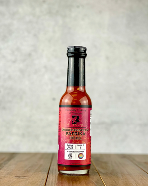 Bottle of Smoked Eggplant Paprika hot sauce from Butterfly Bakery of Vermont on a wood table