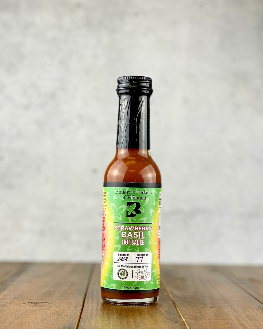 Bottle of Strawberry Basil hot sauce from Butterfly Bakery of Vermont on a wood table