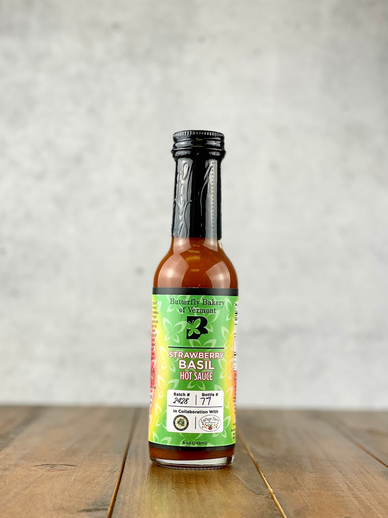Bottle of Strawberry Basil hot sauce from Butterfly Bakery of Vermont on a wood table
