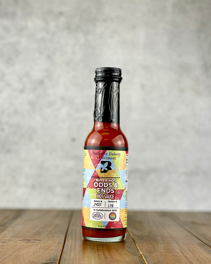 Bottle of Super Hot Odds & Ends hot sauce from Butterfly Bakery of Vermont on a wood table