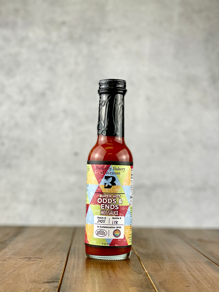 Bottle of Super Hot Odds & Ends hot sauce from Butterfly Bakery of Vermont on a wood table