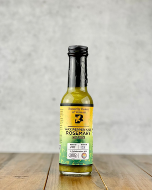 Bottle of Wax Pepper Kale Rosemary hot sauce from Butterfly Bakery of Vermont on a wood table