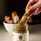 Soft pretzel stick being dipped into a jar of Butterfly Bakery of Vermont Gustard mustard