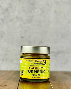 Jar of Garlic Turmeric mustard from Butterfly Bakery of Vermont on a wood table