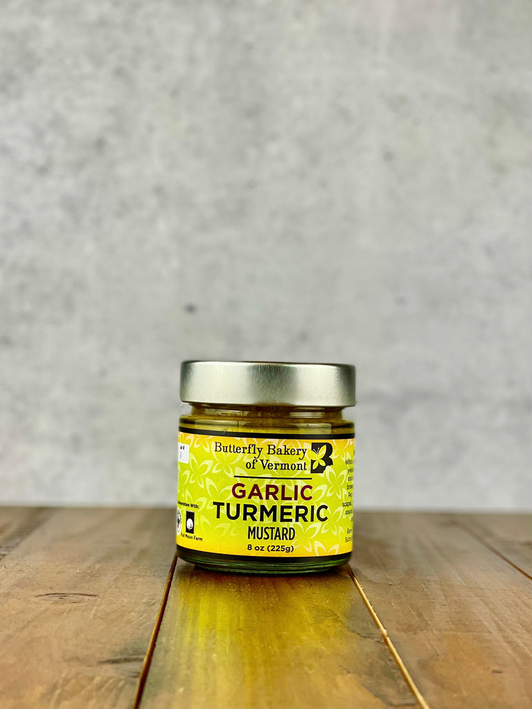 Jar of Garlic Turmeric mustard from Butterfly Bakery of Vermont on a wood table