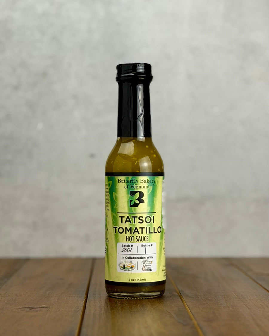 Bottle of Tatsoi Tomatillo hot sauce from Butterfly Bakery of Vermont on a wooden tabletop