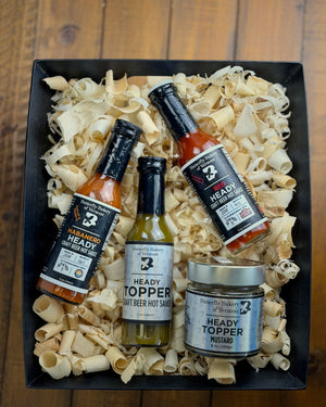 Three bottles of Heady Topper hot sauce and a jar of Heady Topper mustard in a gift basket.