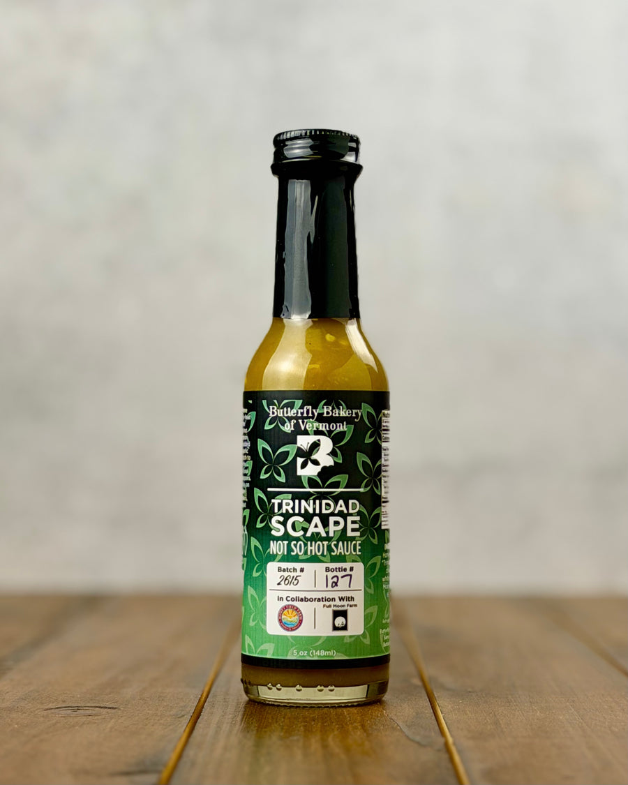 Bottle of Trinidad Garlic Scape sauce from Butterfly Bakery of Vermont on a wooden tabletop